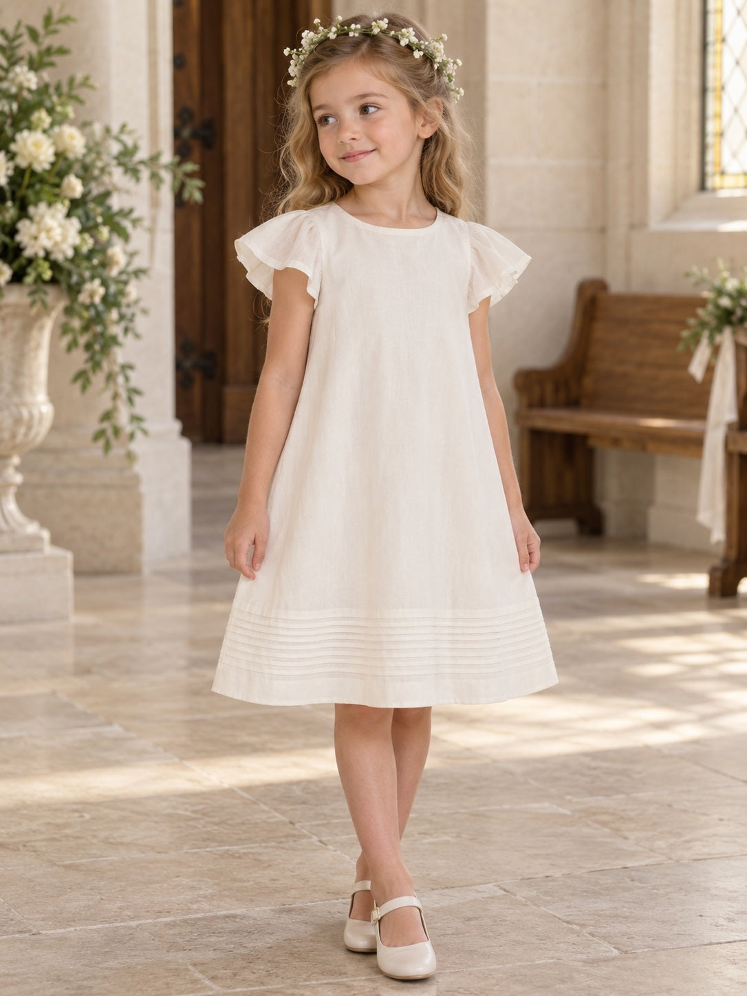 Robe de demoiselle d'honneur simple couleur crème, longueur genou, à étages, manches papillon, base à plis nervurés, coupe droite et boutons au dos