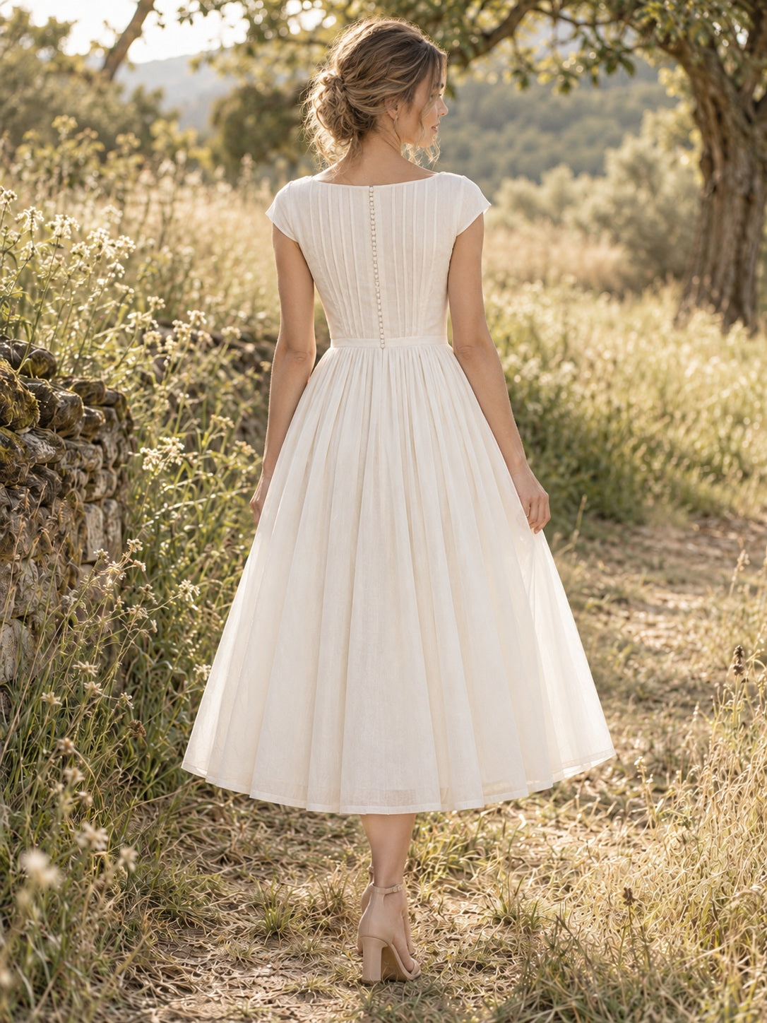 Boho-Brautkleid in Teelänge mit dezentem Bateau-Ausschnitt, feinen Falten und Knopfleiste am Rücken