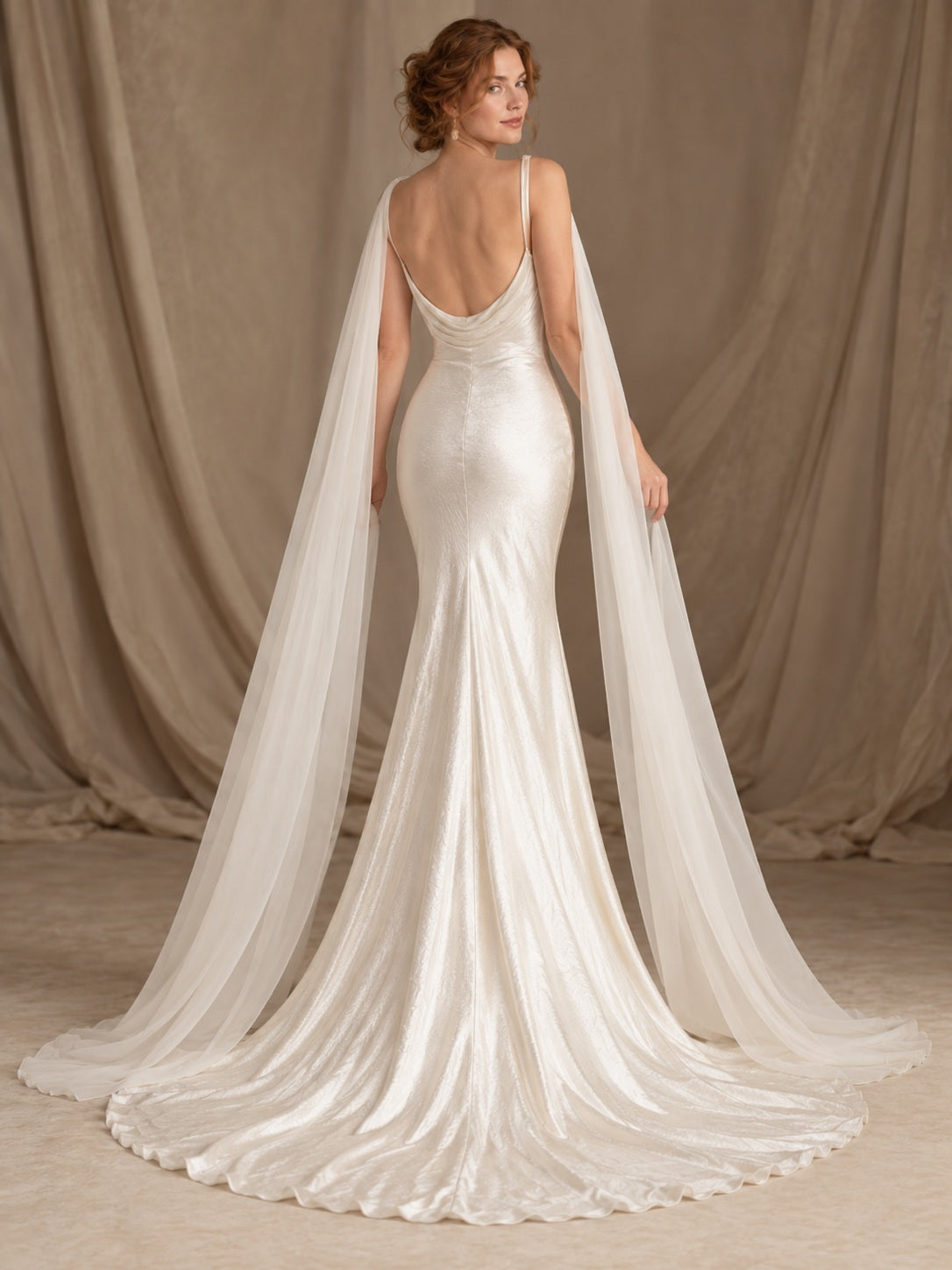 Robe de mariée en satin fluide et ajustée, à fines bretelles spaghetti, encolure bénitier et drapé sur l’épaule