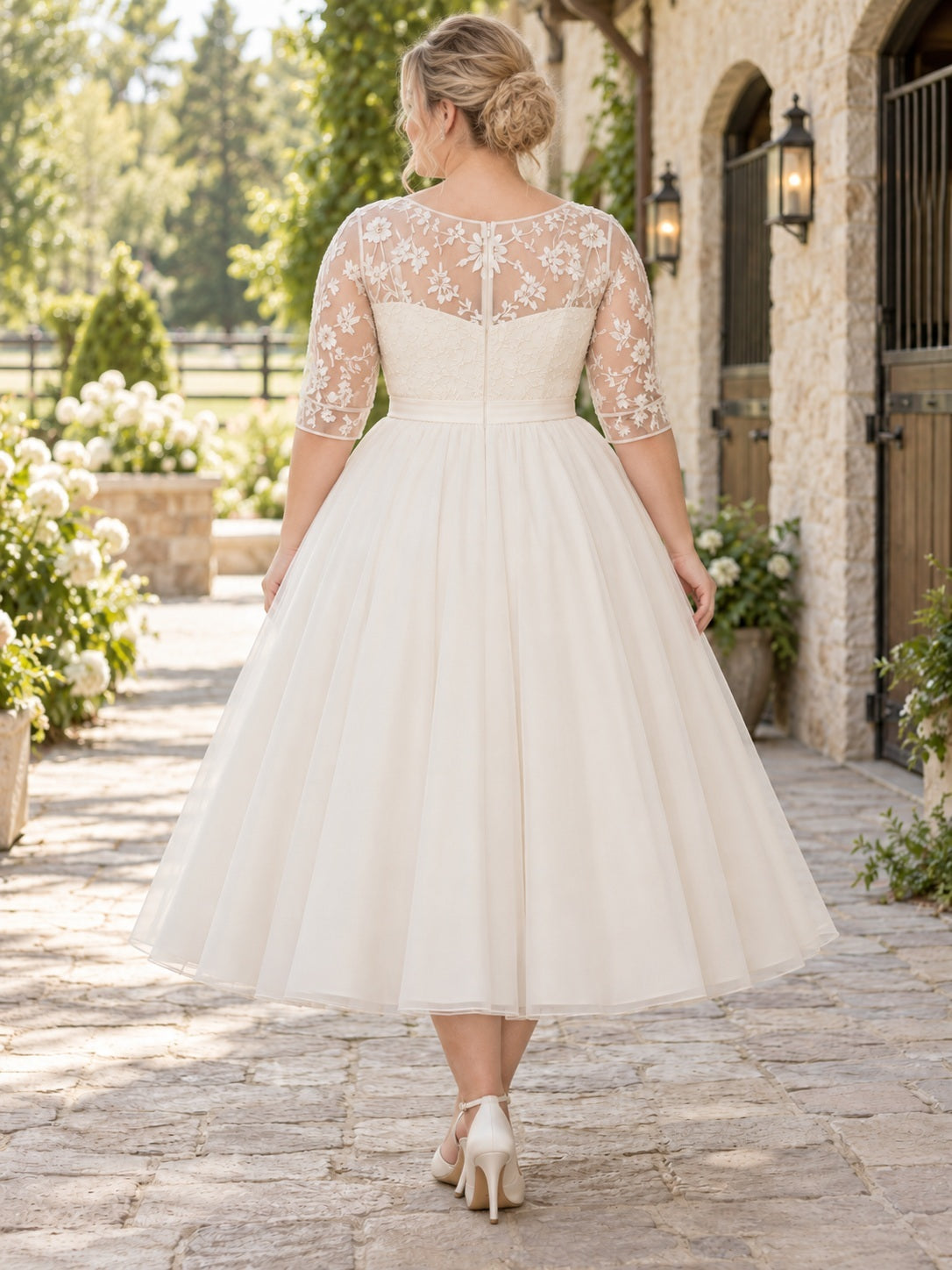 Robe de mariée champêtre en tulle souple et dentelle florale, manches trois-quarts, longueur midi et coupe pudique, grande taille.