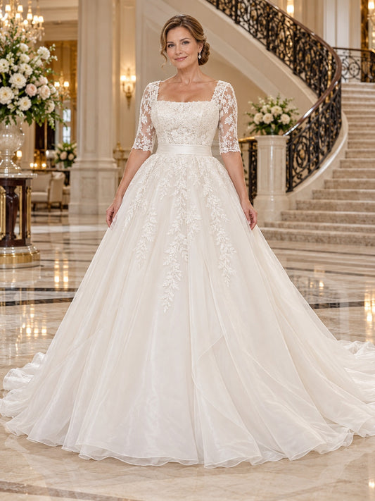 Vestido de novia de tul y encaje en marfil, corte princesa, escote cuadrado, manga al codo y cola corta